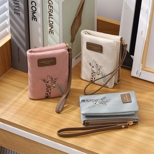 Detail of embroidered giraffe bifold wallets in pastel pink, beige and blue grey colors