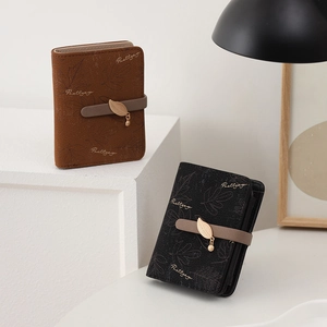 Close-up of mini folding wallets featuring leaf charms and multiple internal card slots