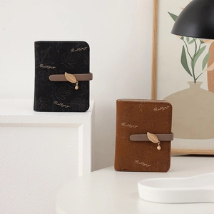 Detail of compact wallets with gold leaf charms and leaf patterns in black and brown