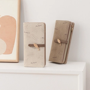 Detail of PU leather long wallets with leaf embossing and metallic leaf pendant charm