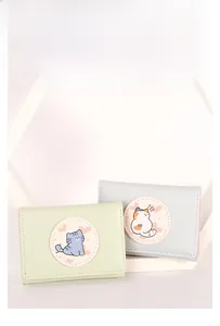Close-up of trifold pastel wallets with cute cartoon cat patches on PU leather