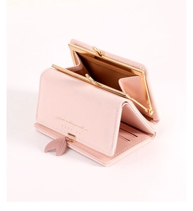 Close-up of pink tri-fold wallet with kiss-lock coin pocket and leaf charm detail