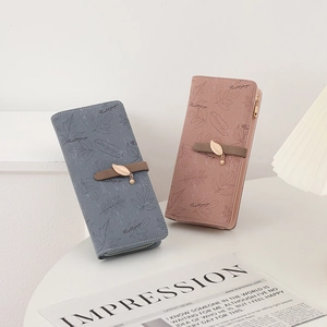 Detail of grey-blue and pink leather wallets with maple leaf print and leaf pendant