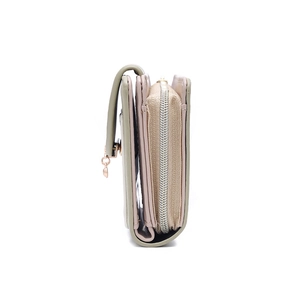 Detail view of multi-compartment green and beige zip wallet with round metal pendant
