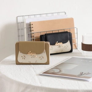 Detailed view of women's floral fold wallets in khaki and black with leaf charms