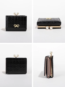 Detail view of black textured leather wallet with gold bow and pearl snap closure