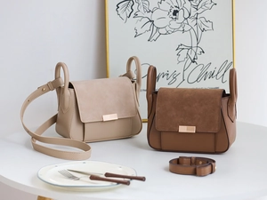 Detail of beige and brown crossbody bags with metal buckles on a white table