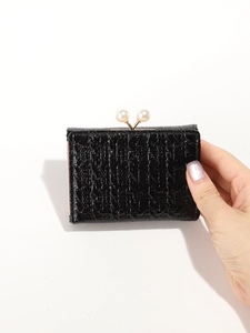 Detail of black crocodile texture wallet with golden frame and twin pearl clasp closure