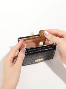 Detailed macro view of black crocodile pattern coin purse with large pearl clasp closure