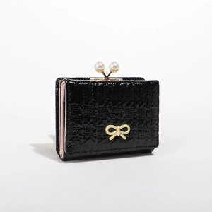 Short black glossy wallet with pearl clasp and golden bow detail on white background