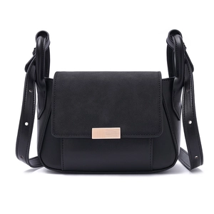 Detail view of the sleek black flap bag with gold rectangular buckle and mixed textures