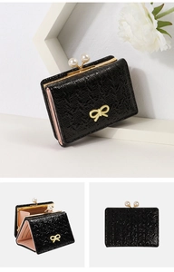 Detail view of tri-fold black PU wallet with pearl clasp, bow accent and pink card slots