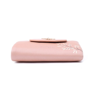 Detail of a pink short PU leather wallet with white leaf pattern and snap button closure