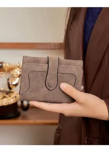 Mini portefeuille rétro en cuir souple marron tenu à la main pour montrer sa taille