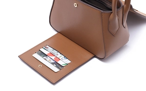 Detail of a brown leather bag showing three functional card slots and magnetic closure
