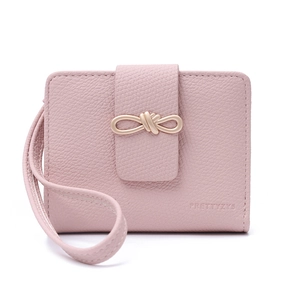 Close-up of pink pebble grain leather wallet with golden bow buckle and wrist strap