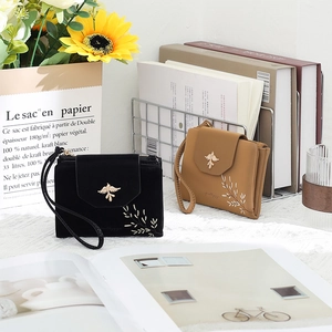 Detail of short PU leather wallets with metal bird clasp and leaf embroidery details