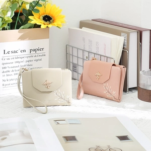 Detailed view of PU leather wallets with floral embroidery and bird buckle charms