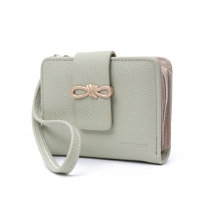 Close-up of light green litchi grain leather wallet featuring golden bow buckle detail