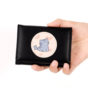 Close-up of black leather wallet with cute cartoon cat patch and pink heart details