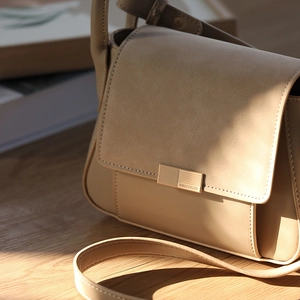 Detailed close-up of premium two-tone stitching on the beige flap shoulder bag
