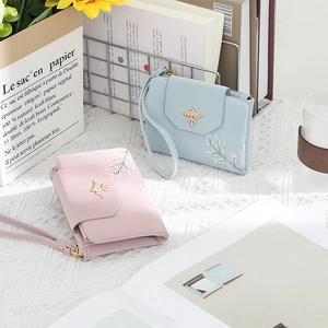Detail of pink and blue short wallets with gold bird clasp and leaf embroidery decor