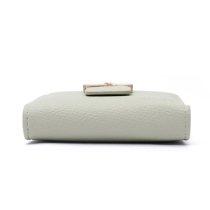 Close-up of light green lychee textured leather wallet showing bottom thickness and stitching
