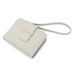 Detail of mint green lychee textured wallet with rose gold bow buckle and wrist strap