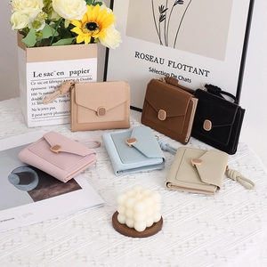 Short envelope-style wallets in six pastel colors on a rustic table with flowers