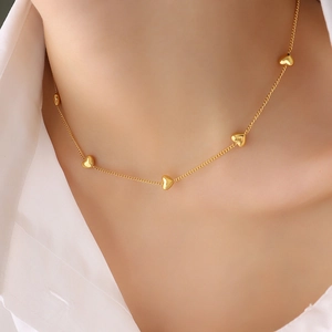 Elegante collar de oro con cinco colgantes de corazón pulidos usado por mujer