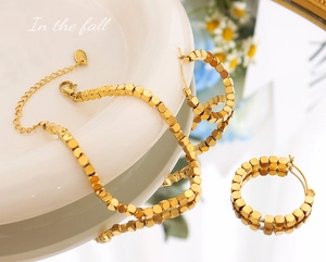 Detail of 18K gold-plated titanium steel jewelry set with movable cubic beads and S.K tag