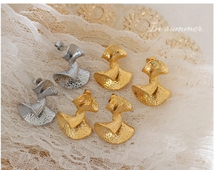 Detail of vintage textured fan-shaped earrings in gold and silver stainless steel