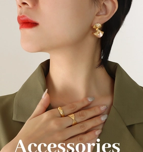 Detailed close-up of retro gold fan earrings and textured rings on a fashion model
