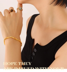 Detail of 18K gold plated beaded bracelet and vintage stone rings on model hand