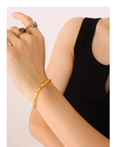 Close-up of a model wearing 18K gold plated bracelet and rings with inlaid gemstones