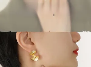 Close-up of golden fan-shaped earrings with vintage hammered texture worn by a model