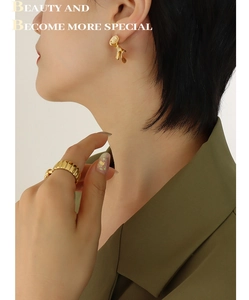 Close-up of gold fan-shaped textured earrings and wavy croissant ring on a model