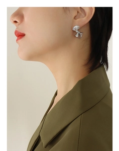 Close-up of silver-toned liquid metal effect twisted earrings worn by a model
