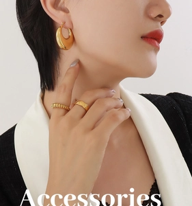 Detailed view of polished 18K gold plated hoop earrings and textured rings on model