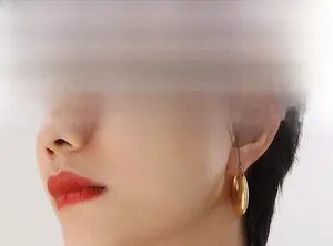 Close-up of chunky gold hoop earrings with polished mirror finish on model ear