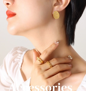 Detail of gold titanium steel oval earrings with embossed rose and chunky chain rings
