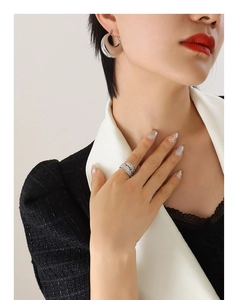 Detail of a model wearing a silver feather ring and thick silver hoop earrings
