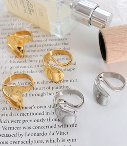 Artistic set of liquid-metal style gold and silver rings on a vintage script background