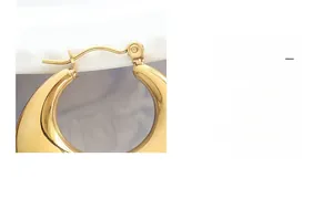 Detail of chunky gold plated stainless steel hoop earring with high polish finish