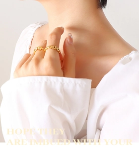 Detailed macro view of gold-plated twisted knot and chunky chain rings on model fingers