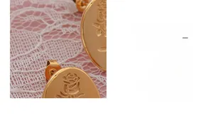 Macro shot of gold-plated titanium steel earrings with embossed rose pattern and pink lace