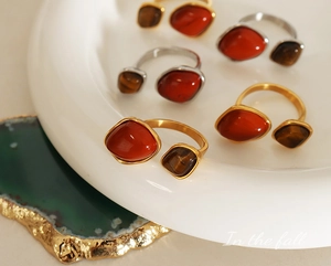 Detail of adjustable gold rings with natural tiger eye and carnelian stones on tray