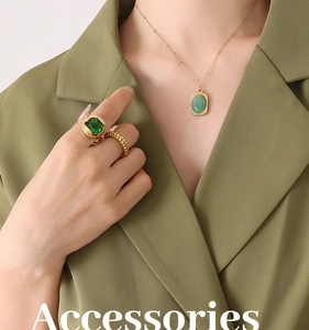 Close-up of 18K gold-plated necklace and rings with green natural stone on green suit