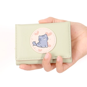 Close-up of a light green tri-fold wallet featuring a cute grey cat and pink heart patch