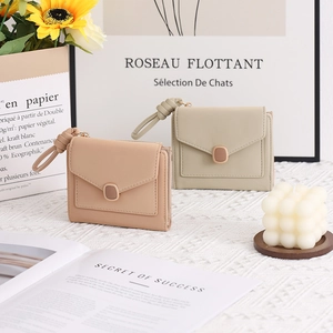 Close-up of minimalist small wallets in dusty pink and beige with envelope flap and knot strap